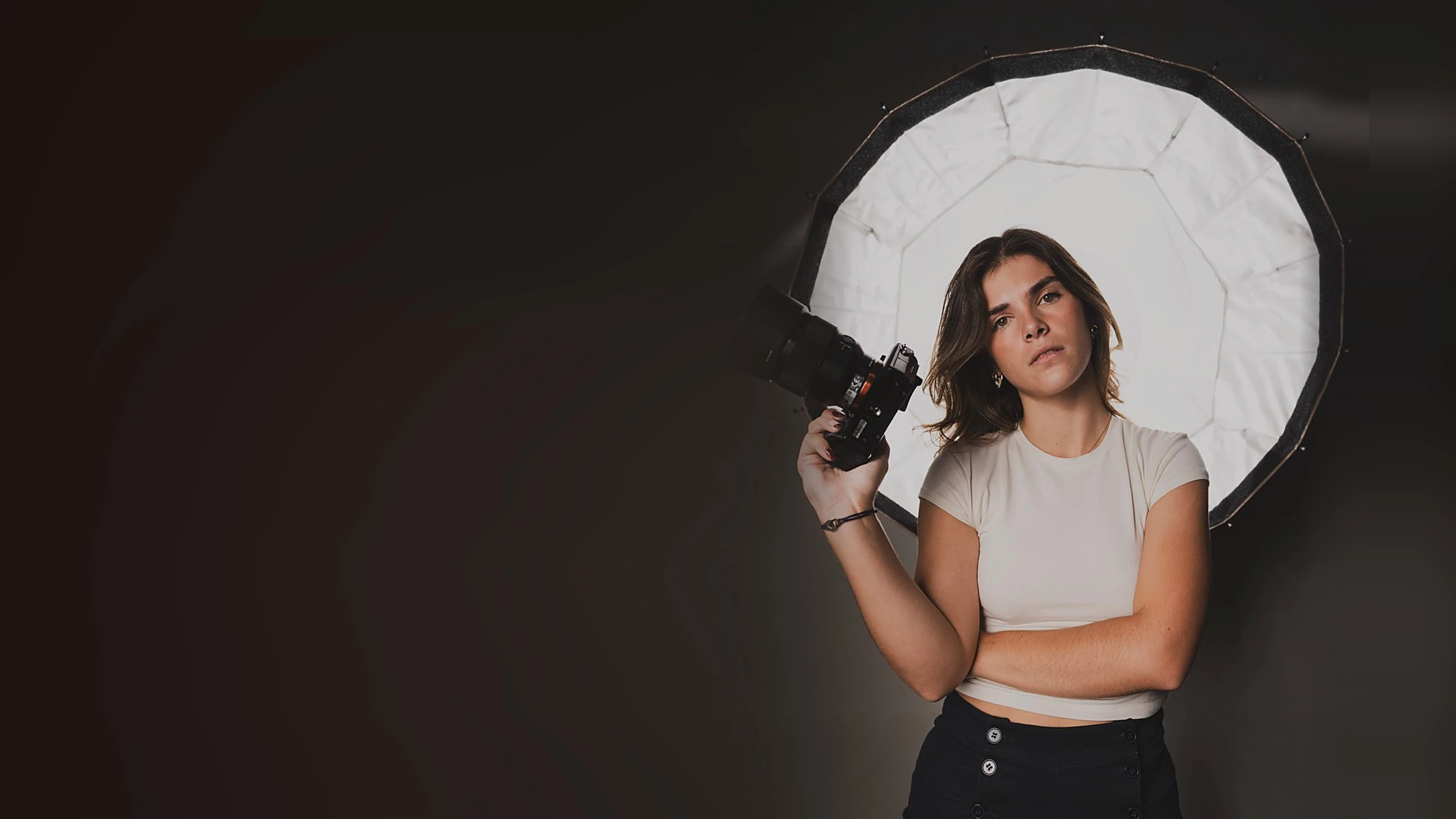 Angèle Octobon, appareil photo à la main, devant une grande boîte à lumière de studio